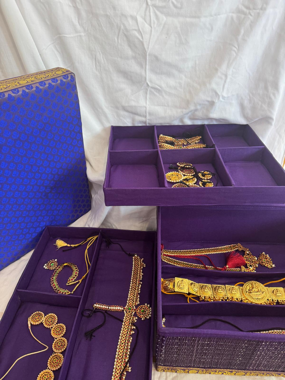 Purple jewelry box with gold jewelry on a white background