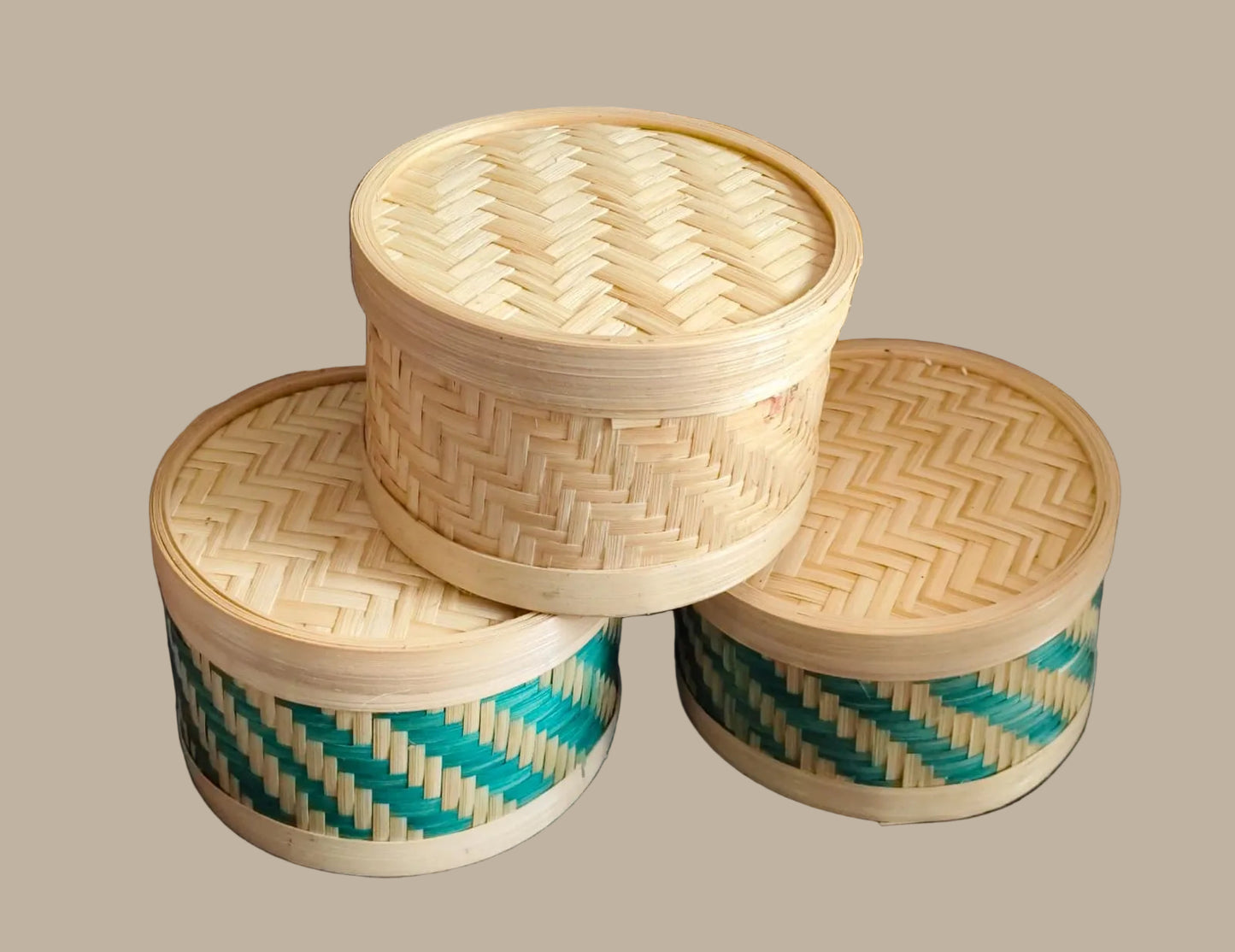 Three woven bamboo containers with lids on a cream baground
