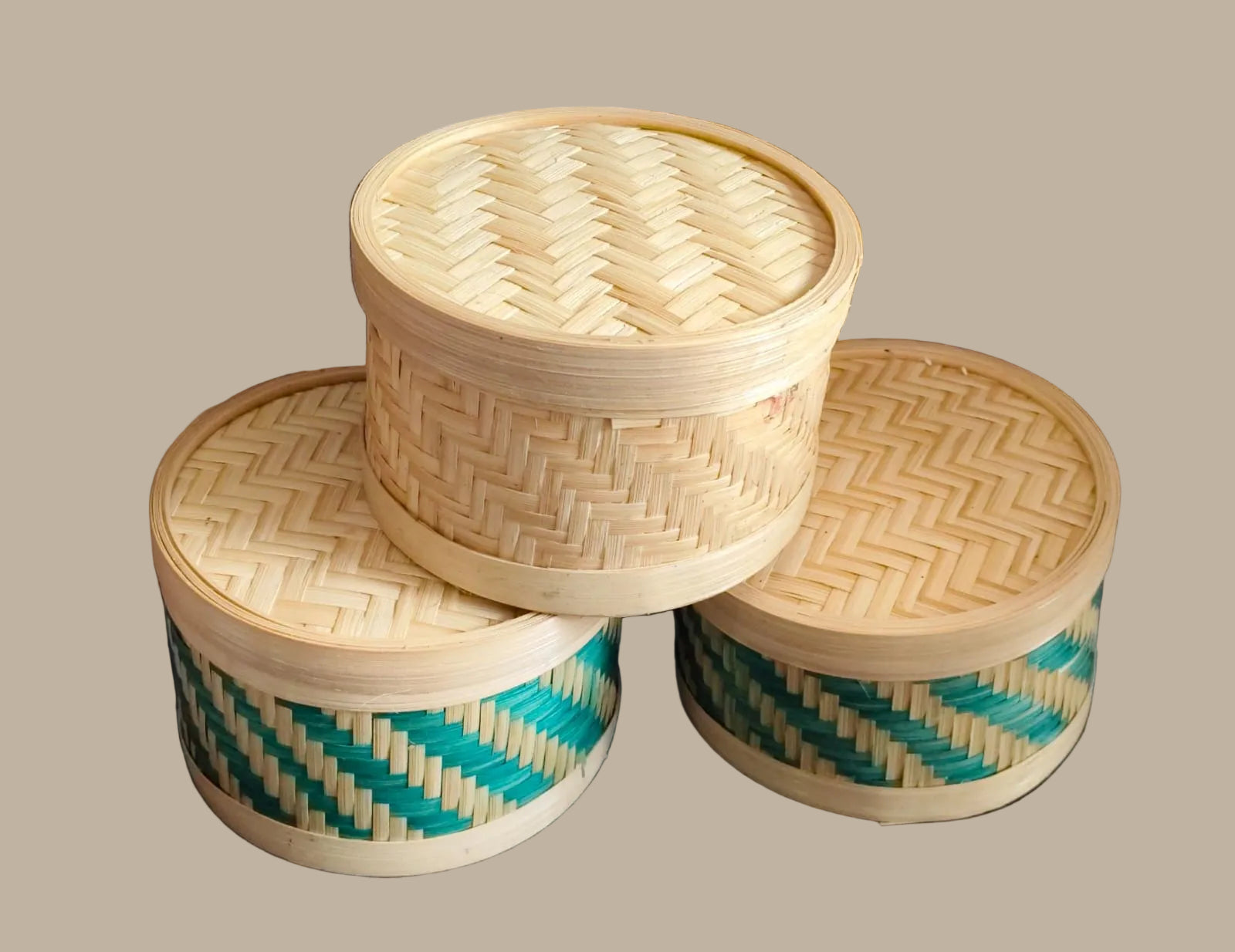 Three woven bamboo containers with lids on a cream baground